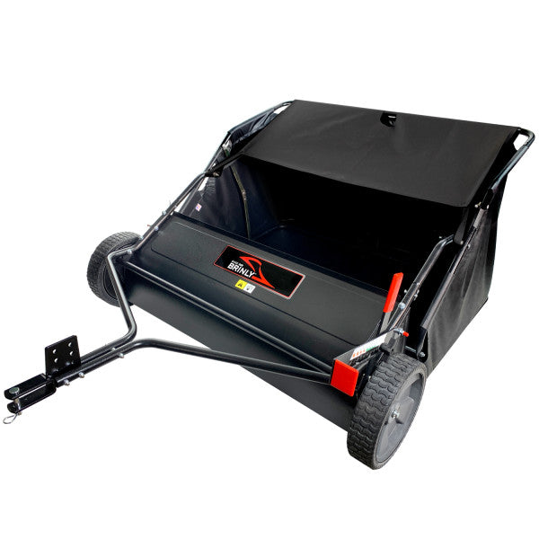 A black and red lawn sweep with two large wheels and a handle attached for towing. It has a fabric collection bag and a metal frame, designed for collecting leaves and debris from lawns.