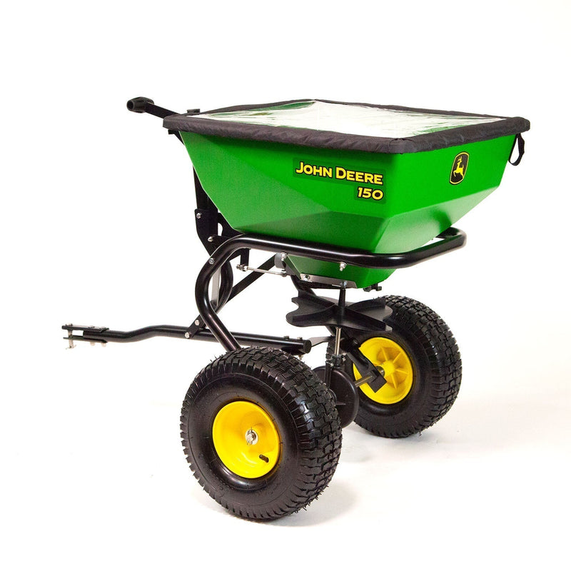 Green and yellow John Deere 150 broadcast spreader with large black wheels and a black frame, designed for lawn and garden use; covered top and tow bar visible.