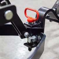 A close-up of a Brinly Parts Magnetic Hitch Pin (5/8 Inch) with bolts and a red pull handle, attached to a black frame on a gray floor—perfect for securing tow-behind lawn equipment.