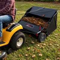A person on a yellow riding lawn mower pulls a Brinly Parts 42″ Lawn Sweeper with DOUBLE-HELIX Brushes (LS2-42BH2-G), efficiently collecting autumn leaves on a grassy lawn.