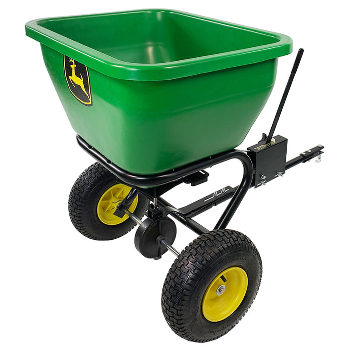 The John Deere Tow Broadcast Spreader, model LPBS36JD, features a green polyethylene hopper with a large rectangular tub. It has two black wheels with yellow hubs, a black metal frame and handle, and offers patented directional spread for efficient use.