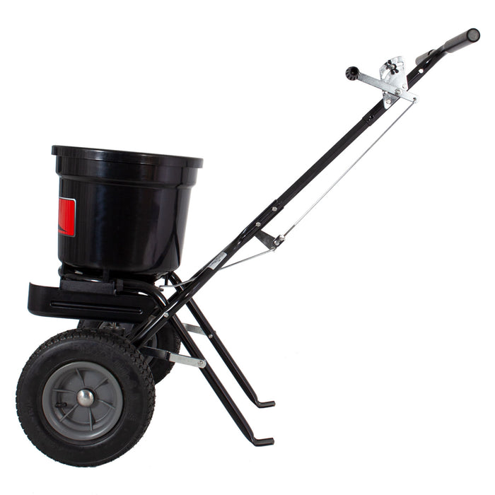 The Brinly Parts 50 LB. Push Spreader with Deflector Kit, model P20-500BHDF, is a black heavy-duty spreader ideal for seeds or fertilizer. It features a long handle, metal support legs for stability, and an optional deflector kit for precise application.