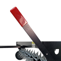 The close-up shows a Brinly Parts SAT2-40BH-G 40″ Tow-Behind Spike Aerator with a black metal lever featuring a red handle, positioned above a spiked silver roller. The sharp protrusions of the roller indicate its use for efficient lawn aeration and processing.