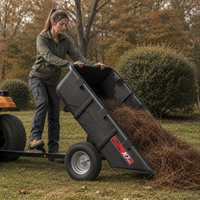 A woman tips a Brinly Parts 10 Cu. Ft. Poly Cart (Model PCT-101BH), attached to a yellow mower, to unload pine straw or yard debris onto a grassy lawn surrounded by trees and bushes.
