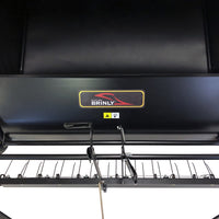 Close-up of a black Brinly Parts 42″ Lawn Sweeper with Dethatcher (STS-42BHDK-A), featuring the company logo, warning label, and portions of the metal frame and sweeper brush assembly.