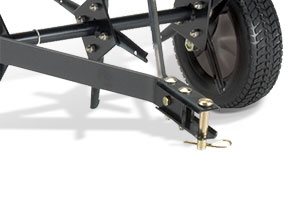 Close-up of a black metal tow bar and wheel assembly on a garden cart or trailer. The tow bar has bolts and a safety pin for attachment. A large, textured wheel is visible in the background, partially in shadow.