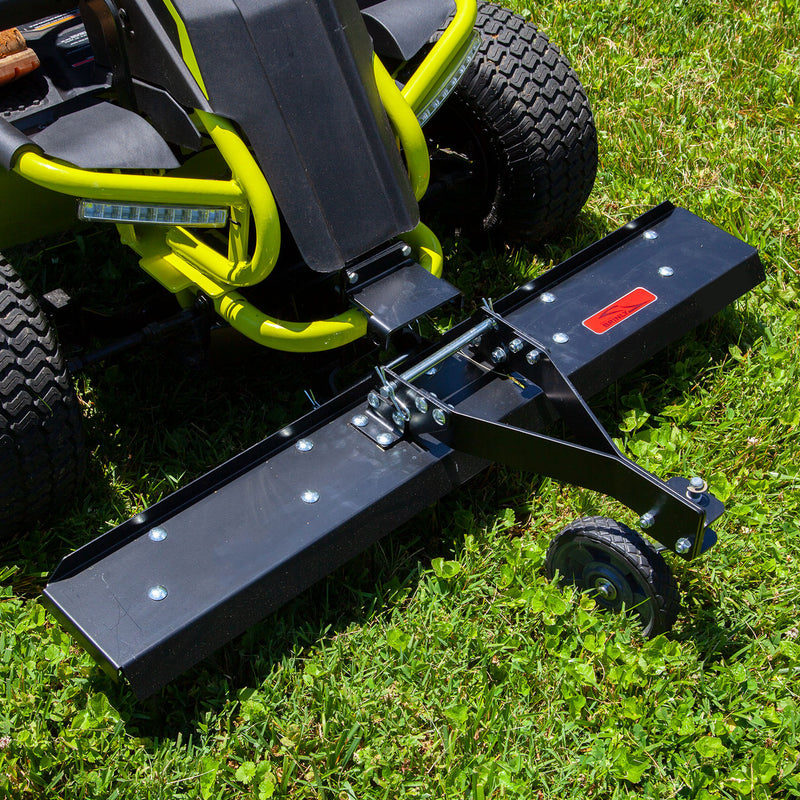 A close-up of a RYOBI Electric Riding Mower featuring a Brinly Parts 38 in. Front Mount Dethatcher (DT-38RY) on green grass. The dethatcher, with a red label and small support wheel, along with the mowers robust tires and sturdy build, is ideal for any yard project.