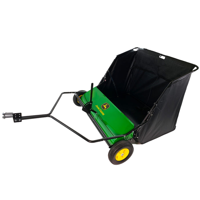 The John Deere 42 Tow-Behind Lawn Sweeper, model LPSTS-42JD / STS-42JD, features a green and black design with yellow wheels. It includes a tow bar for easy towing, a high-capacity hamper for debris collection, and the signature John Deere logo on its side.