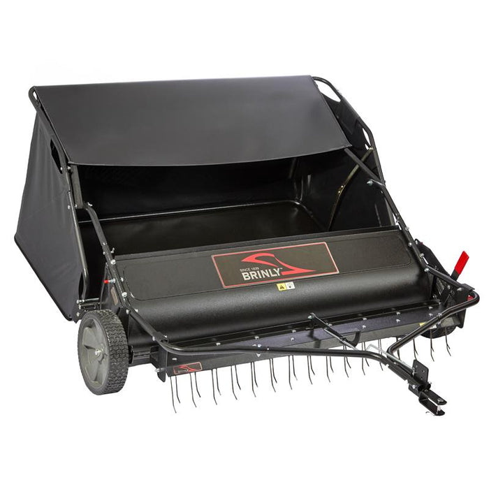 The Brinly Parts 54″ Combo Lawn Sweeper with Dethatcher (LSDT2-54BH-G) features a wide collection hopper, sturdy wheels, and metal tines for effective turf maintenance. The Brinly brand is displayed on the front.