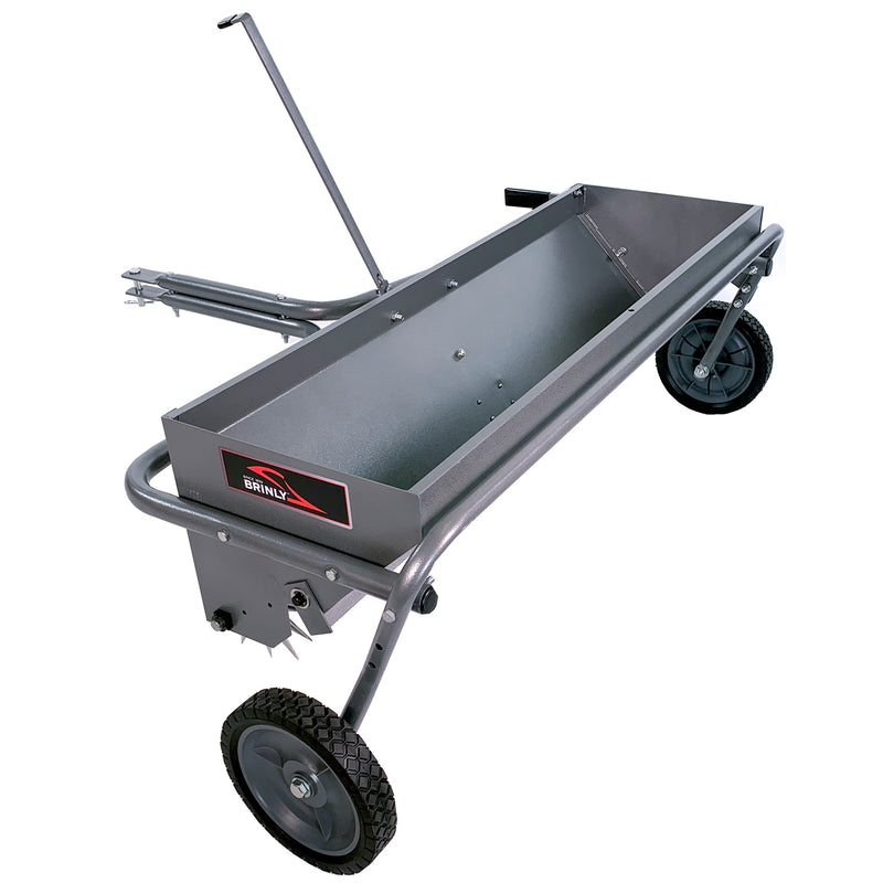 The Brinly Parts 40 Combination Aerator Spreader in Hammered Gunmetal (AS2-40BH-S) features a metal frame with two wheels, a handle, and a rectangular hopper for material distribution. It has a steel drop spreader with a hitch attachment positioned sideways to highlight its length and structure.