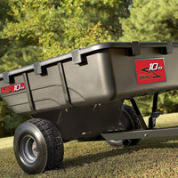 A black Brinly Parts 10 Cu. Ft. Poly Cart (PCT-101BH) with large wheels sits on grass outdoors, sunlight shining and trees in the background.