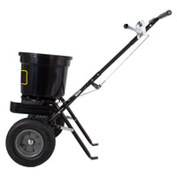 The Brinly Parts 50 LB. Push Spreader with Side Deflector & Hopper Cover (P20-500BHDF-A2) is a black, heavy-duty two-wheeled spreader with a large adjustable bucket and metal frame for spreading seed or fertilizer on your lawn or garden.