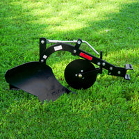 The Brinly Parts Sleeve Hitch Moldboard Plow | PP-510, with its curved blade and disc, rests on green grass. Its metal arms signal its a tractor attachment. The sunlit lawn backdrop perfectly highlights its robust design.