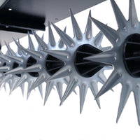 Low-angle close-up of star-shaped gears from Brinly Parts 40″ Tow-Behind Spike Aerator (SAT2-40BH-G) mounted on a rod. The bright white background highlights their metallic sheen and intricate texture, showcasing precision engineering in lawn aeration equipment.