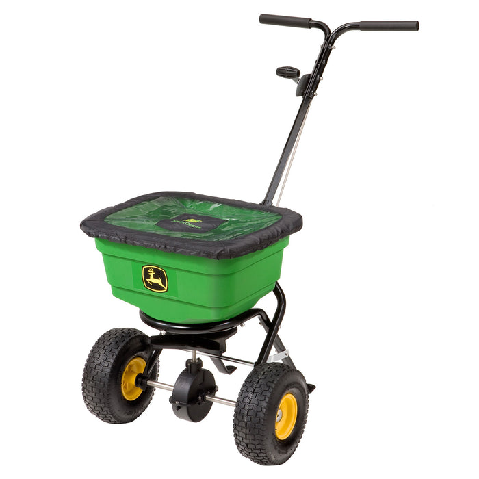 The John Deere All-Season Push Broadcast Spreader LP31340L/LP31340, by John Deere, is a green and black tool with four rugged wheels, an ergonomic split handle, and a durable poly hopper for even distribution. It features a yellow logo on its broad base for tackling various terrains effortlessly.